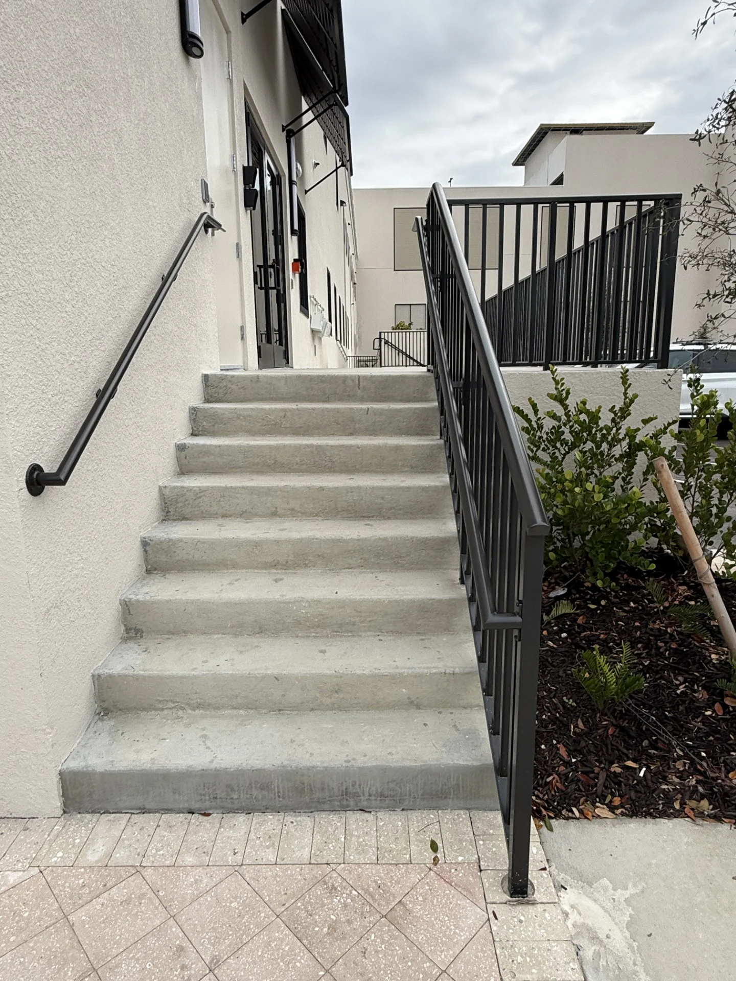 Brooks & Freund – Bimini Square – Bahama Shutters – Stair Rail – Wall Mounted Grab Rail (1) Aluminum bahama shutters mounted above exterior windows at Bimini Square