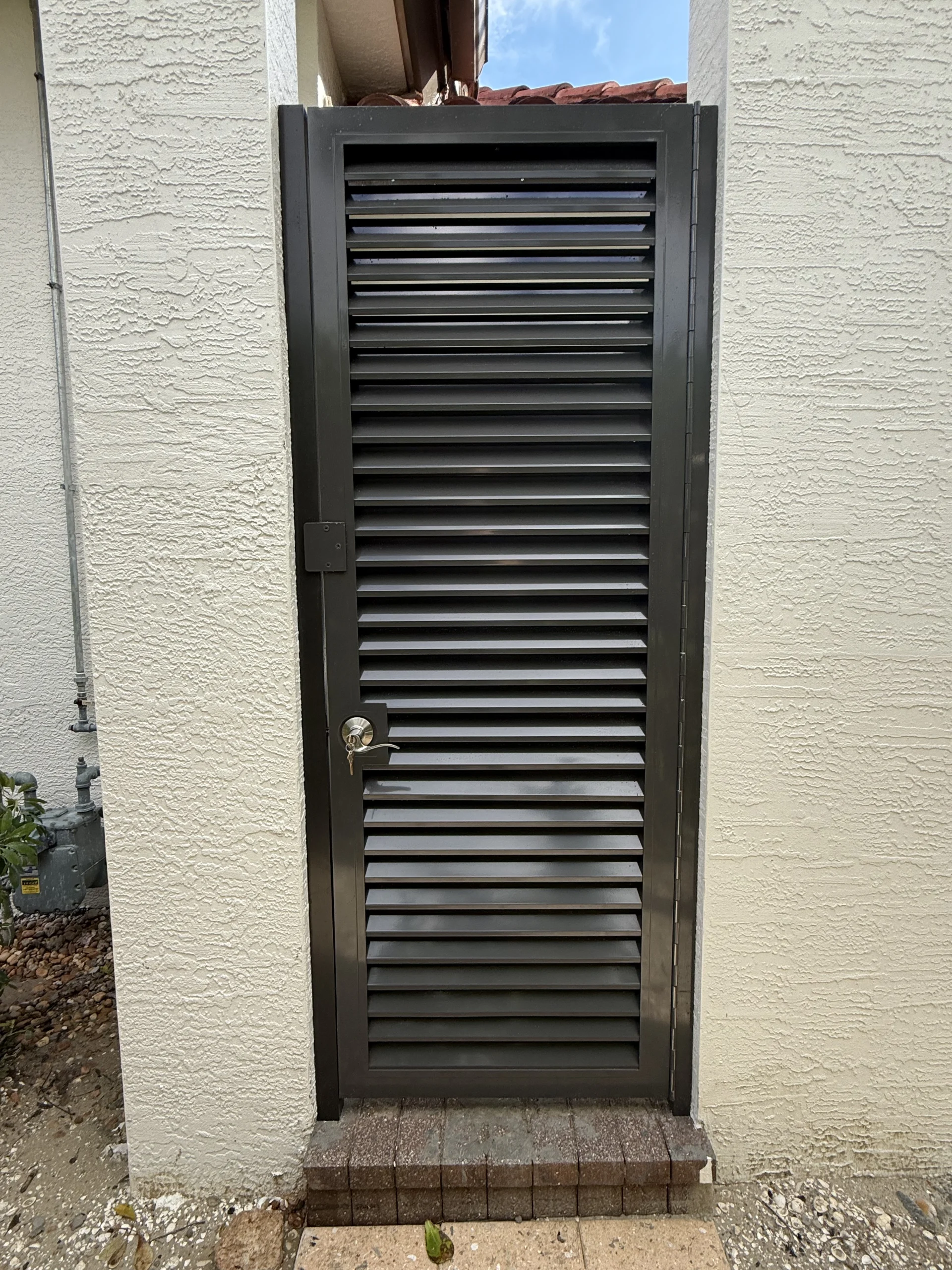 Paterra Custom Homes – Outdoor Louvered Shower Door Fixed aluminum louver panel fabricated for Paterra Custom Homes